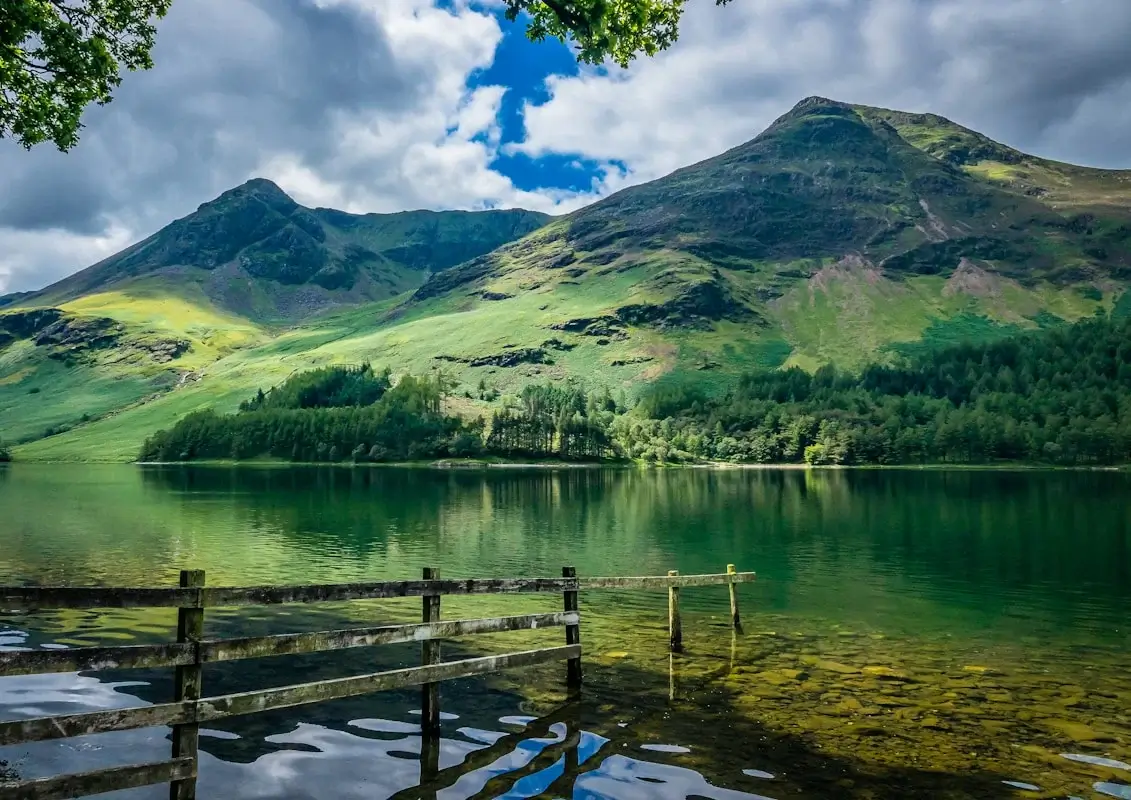 View across a deep ribbon lake with craggy fells reflected in still water in the Lake District